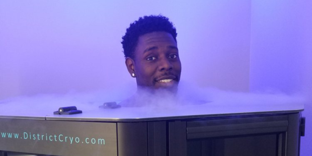 A man relaxes in a hot tub illuminated by blue light, enjoying a soothing and therapeutic experience.
